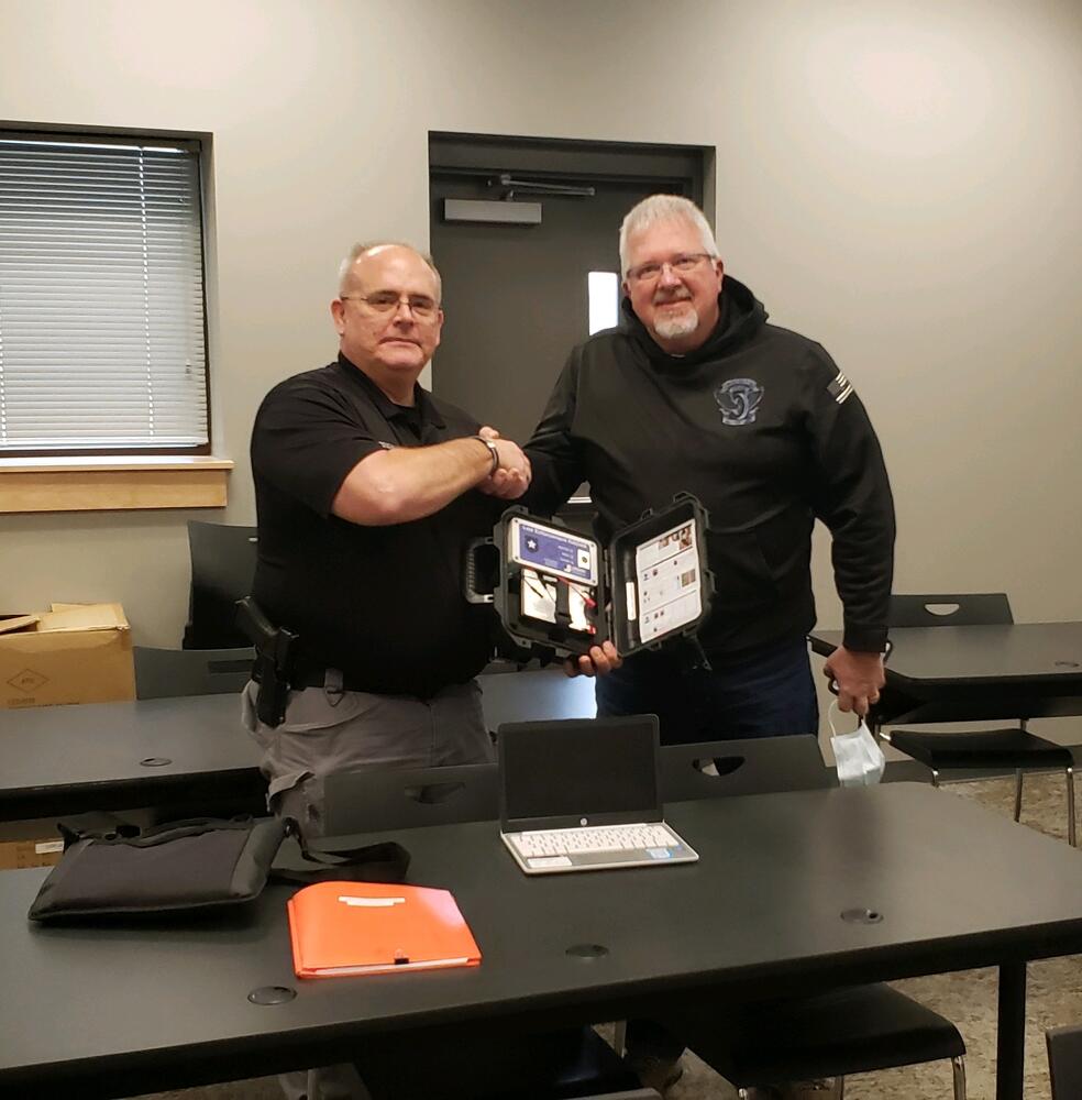 Sheriff Martin and Daniel Kiser hold new radar in a black box.